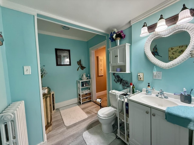 bathroom featuring toilet, radiator heating unit, ornamental molding, vanity, and wood finished floors