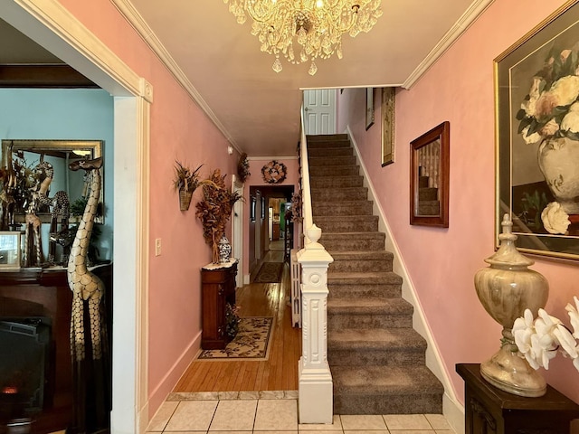 stairs featuring a notable chandelier, baseboards, tile patterned floors, and crown molding