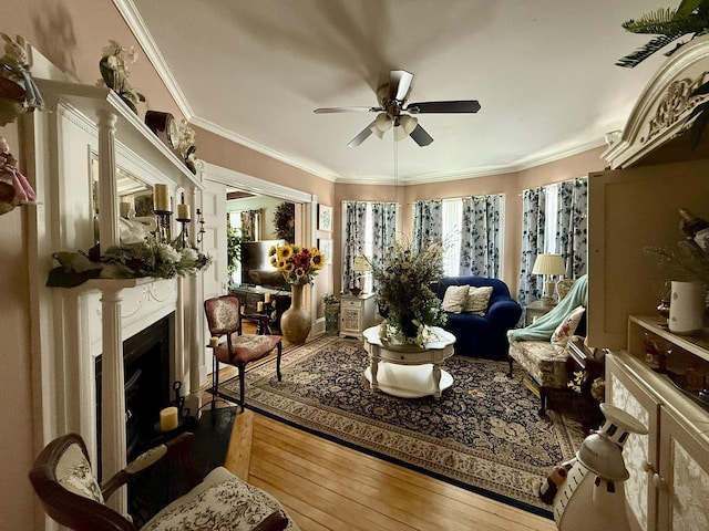 living area featuring ornamental molding, hardwood / wood-style floors, a fireplace, and a healthy amount of sunlight