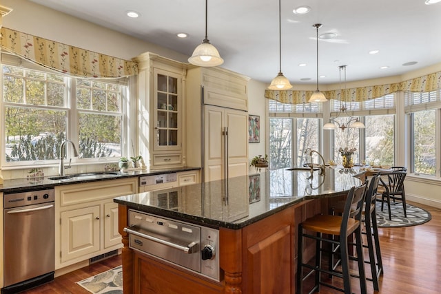 kitchen with paneled built in fridge, cream cabinets, a sink, and a warming drawer