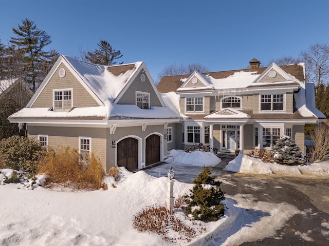 shingle-style home featuring an attached garage and a chimney