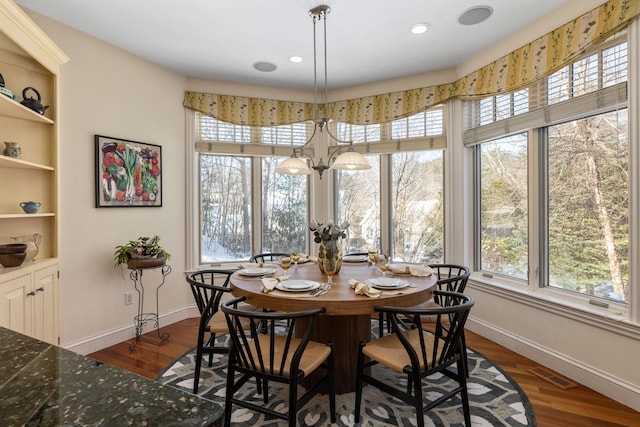 dining space featuring baseboards, visible vents, dark wood finished floors, and a notable chandelier