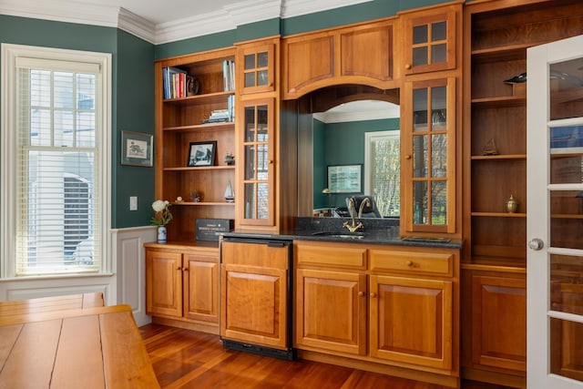 bar featuring arched walkways, dark wood finished floors, a wainscoted wall, crown molding, and a sink