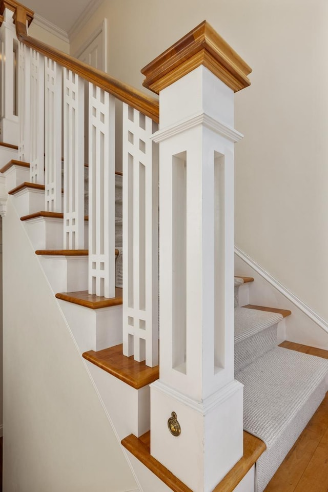 staircase featuring ornamental molding and wood finished floors