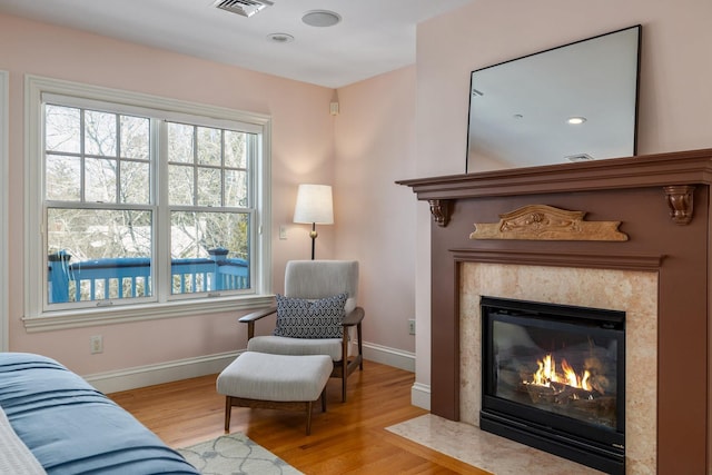 sitting room with visible vents, a fireplace, baseboards, and wood finished floors