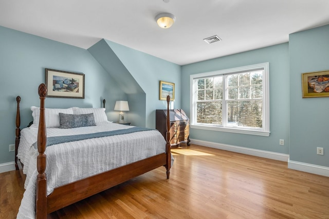 bedroom with baseboards, visible vents, and wood finished floors