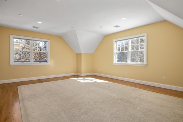 bonus room featuring lofted ceiling, baseboards, visible vents, and wood finished floors