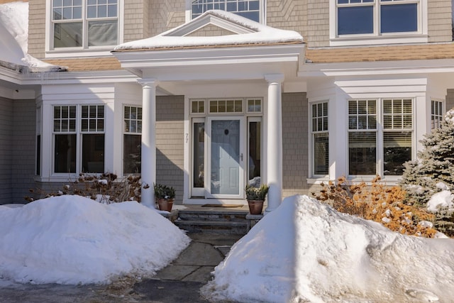 view of exterior entry with roof with shingles