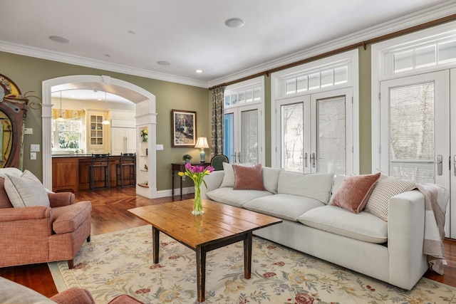 living room with arched walkways, french doors, crown molding, and wood finished floors