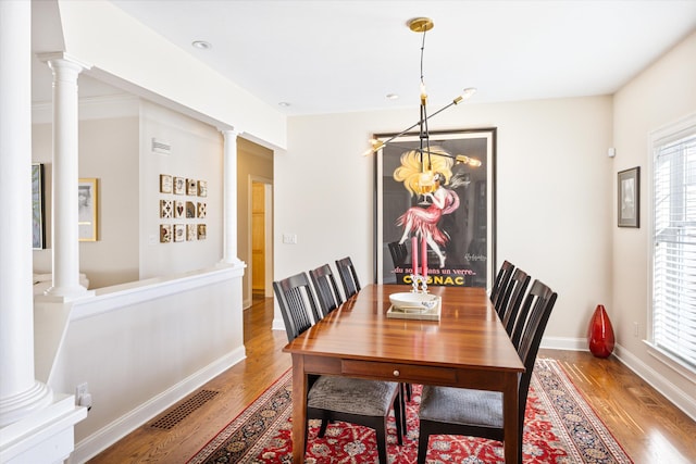 dining area featuring visible vents, wood finished floors, and decorative columns