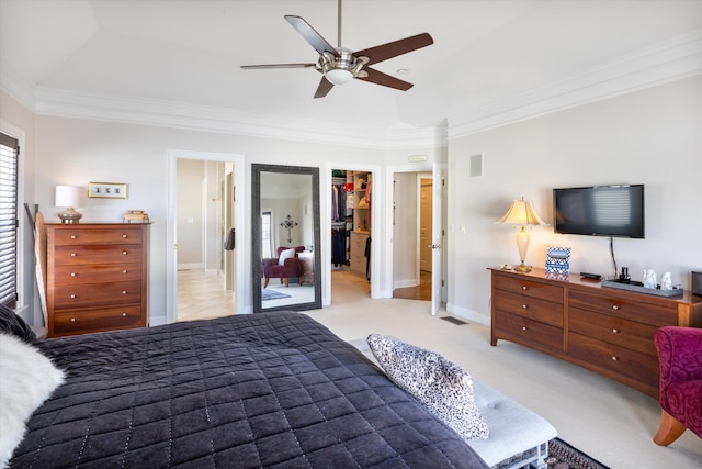 bedroom featuring crown molding, a spacious closet, baseboards, and light colored carpet