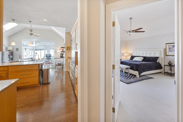 hallway featuring lofted ceiling, crown molding, and light wood-style floors