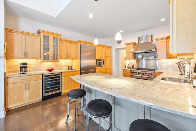 kitchen featuring built in appliances, wine cooler, a peninsula, a sink, and wall chimney range hood