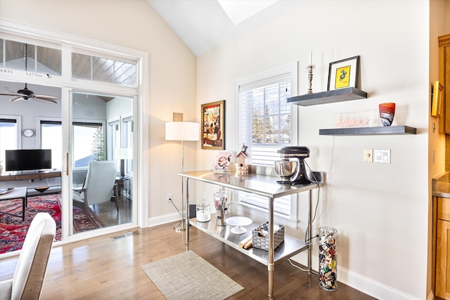 interior space with lofted ceiling with skylight, baseboards, visible vents, and wood finished floors