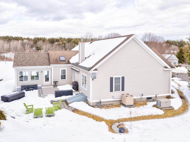 snow covered back of property featuring entry steps and a chimney