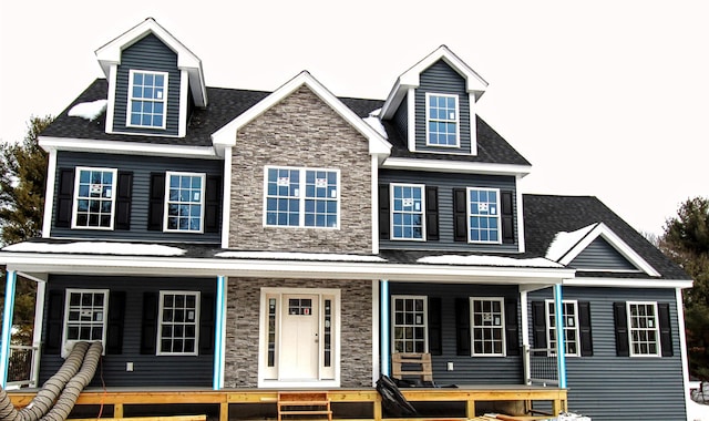 view of front of property featuring covered porch, stone siding, and a shingled roof