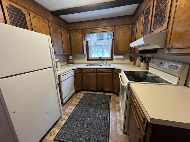 kitchen with white appliances, under cabinet range hood, light countertops, and a sink