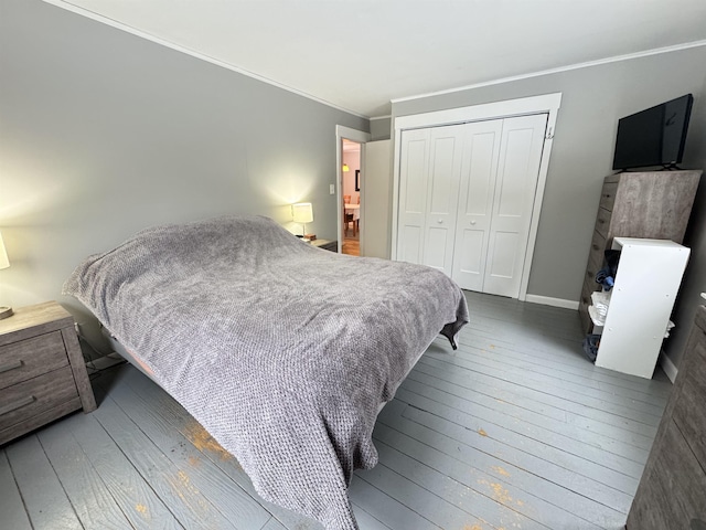 bedroom with baseboards, a closet, hardwood / wood-style flooring, and crown molding