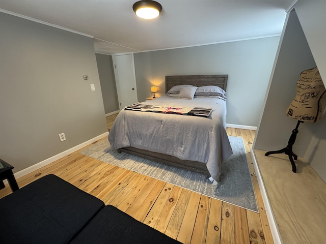 bedroom with ornamental molding, light wood-type flooring, and baseboards