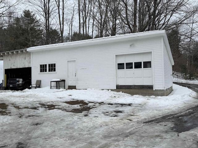 snow covered garage featuring a detached garage