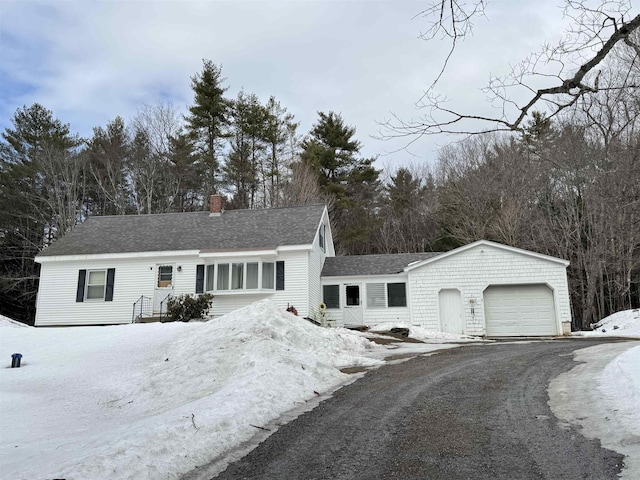 view of front of home featuring a shingled roof, driveway, a chimney, and an attached garage