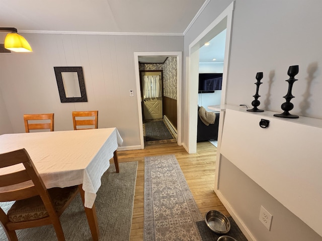 dining area with light wood-style flooring and ornamental molding