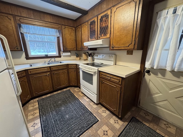 kitchen featuring white appliances, light floors, light countertops, under cabinet range hood, and a sink