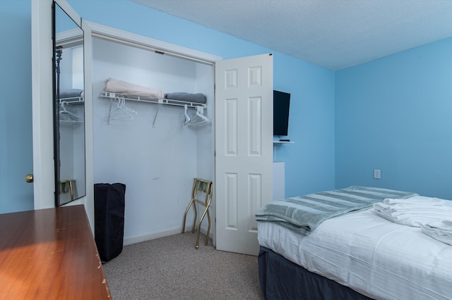 bedroom with a textured ceiling, a closet, carpet, and baseboards