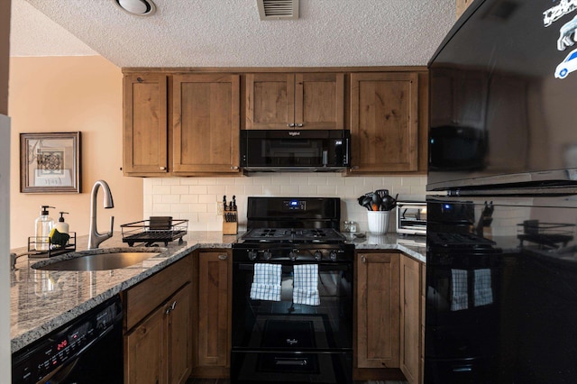 kitchen featuring light stone counters, visible vents, backsplash, a sink, and black appliances