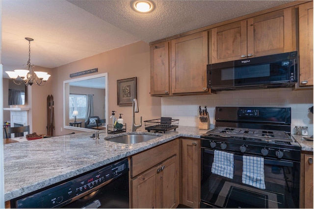 kitchen featuring a sink, a peninsula, black appliances, and light stone countertops