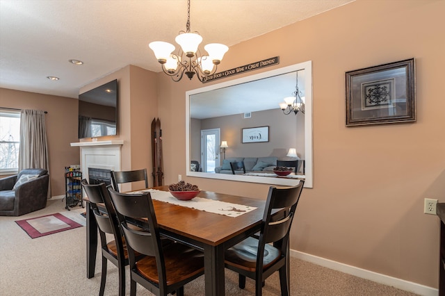 dining room featuring baseboards, visible vents, carpet, a fireplace, and a notable chandelier