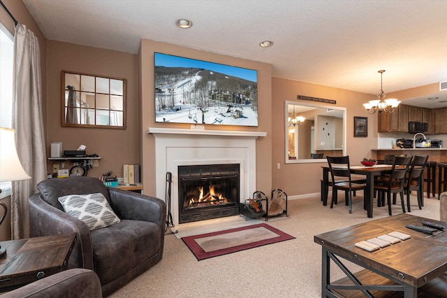 living area with a large fireplace, visible vents, baseboards, an inviting chandelier, and carpet floors