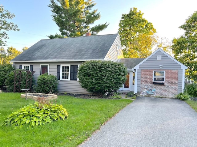 view of front of home with aphalt driveway, a front lawn, a shingled roof, and brick siding