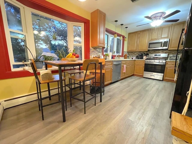 kitchen with decorative backsplash, decorative light fixtures, stainless steel appliances, light countertops, and light wood-style floors