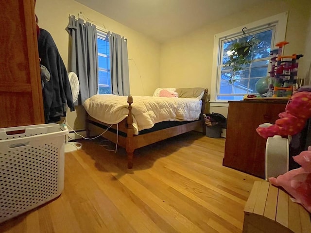 bedroom with light wood finished floors and a baseboard radiator