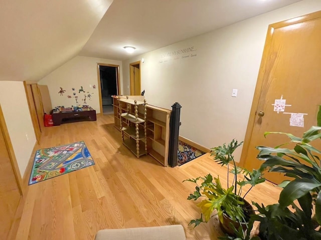 interior space with vaulted ceiling, an upstairs landing, and wood finished floors