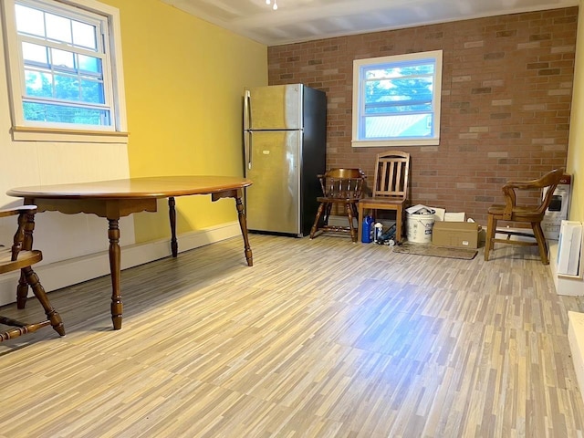 office featuring light wood finished floors, brick wall, and baseboards