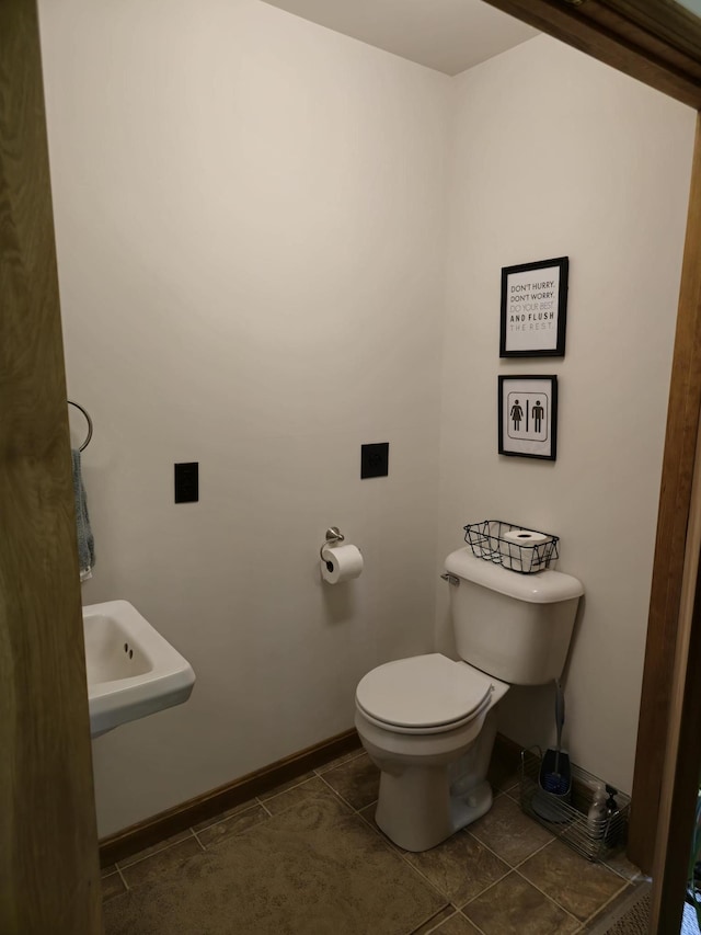 bathroom featuring baseboards, a sink, toilet, and tile patterned floors