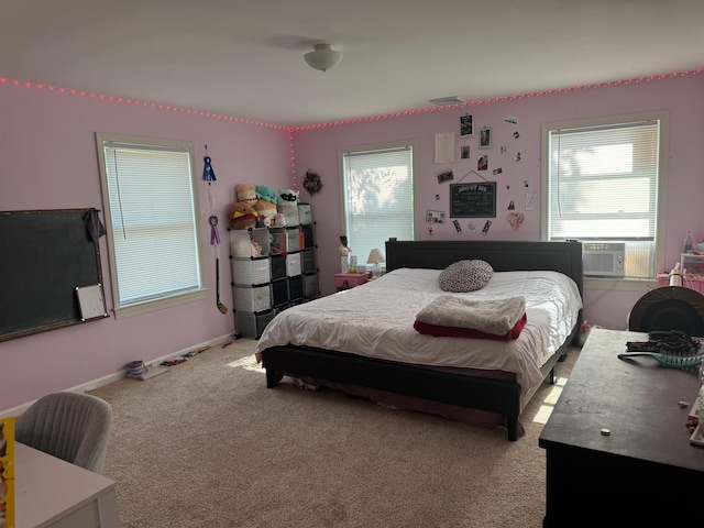 bedroom with cooling unit, light carpet, and baseboards