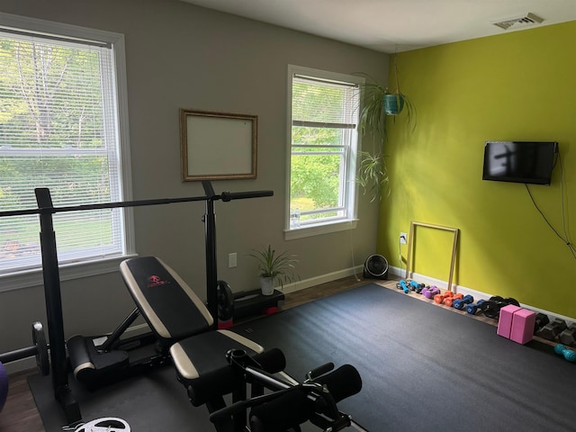 workout room with dark wood-style floors, baseboards, and visible vents