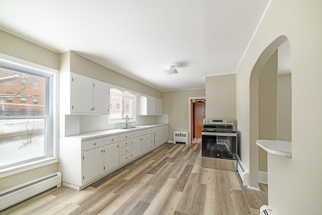 kitchen featuring radiator heating unit, stainless steel electric range oven, baseboard heating, light countertops, and a sink