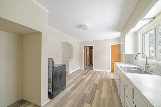 kitchen with white cabinets, light wood-style flooring, baseboard heating, light countertops, and a sink