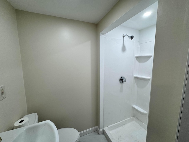 bathroom featuring baseboards, a shower stall, and toilet