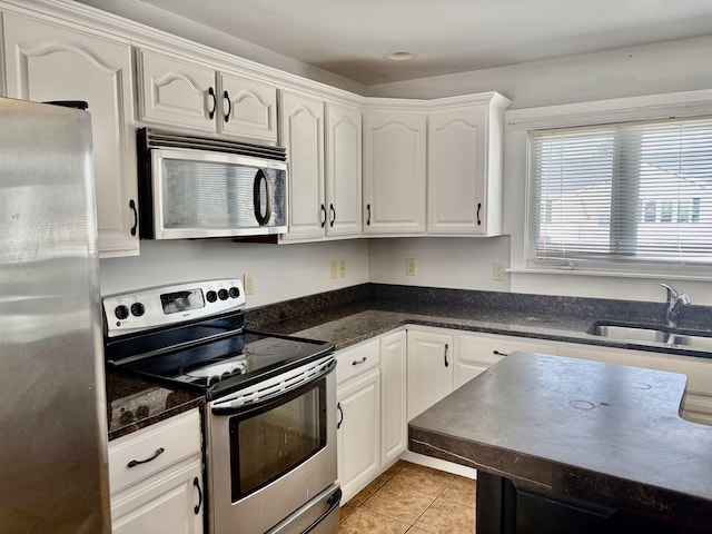 kitchen with appliances with stainless steel finishes, white cabinetry, a sink, and light tile patterned floors