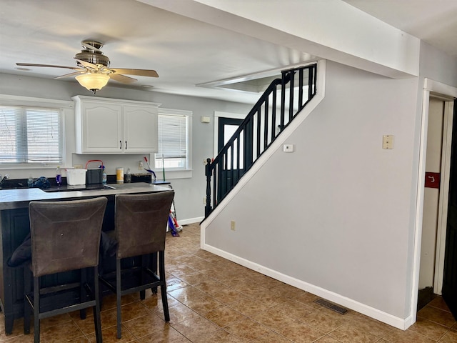 dining room with baseboards, visible vents, a ceiling fan, stairs, and light tile patterned flooring