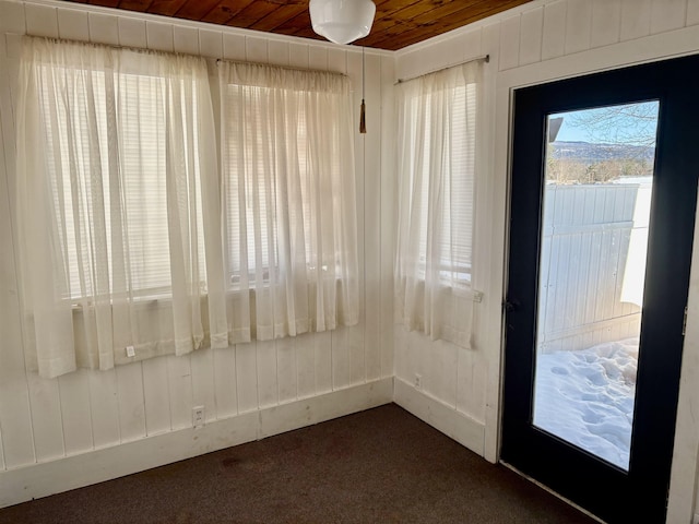 empty room with wooden ceiling, wooden walls, and dark carpet