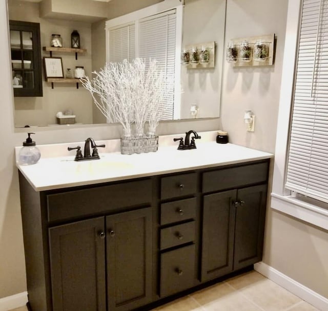 full bathroom featuring tile patterned flooring, a sink, baseboards, and double vanity