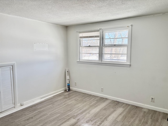 spare room featuring a textured ceiling, wood finished floors, and baseboards