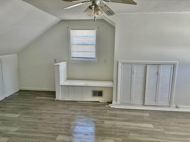 bonus room with visible vents, a ceiling fan, lofted ceiling, wood finished floors, and a textured ceiling