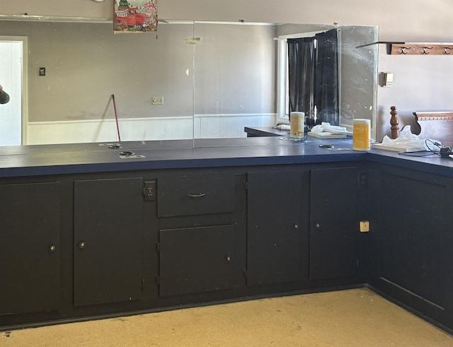 kitchen featuring a wainscoted wall and dark cabinetry